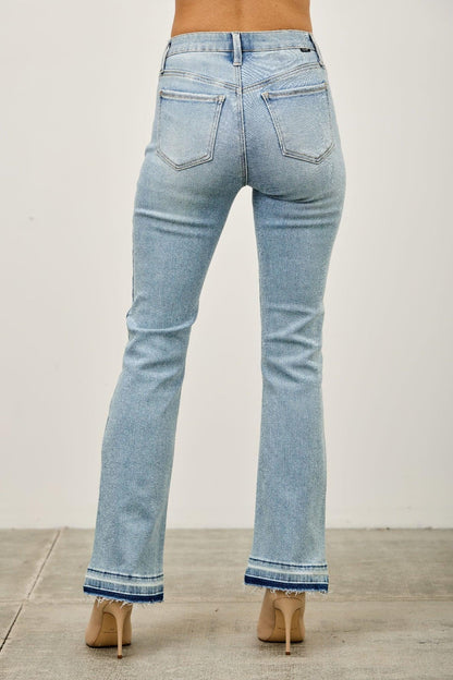 Back view of light wash bootcut jeans with frayed hem, worn with nude heels