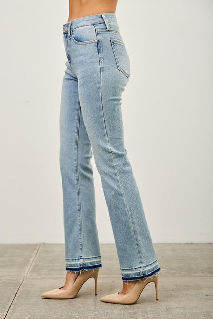 Light wash straight leg jeans with raw hem, styled with nude heels on a model.