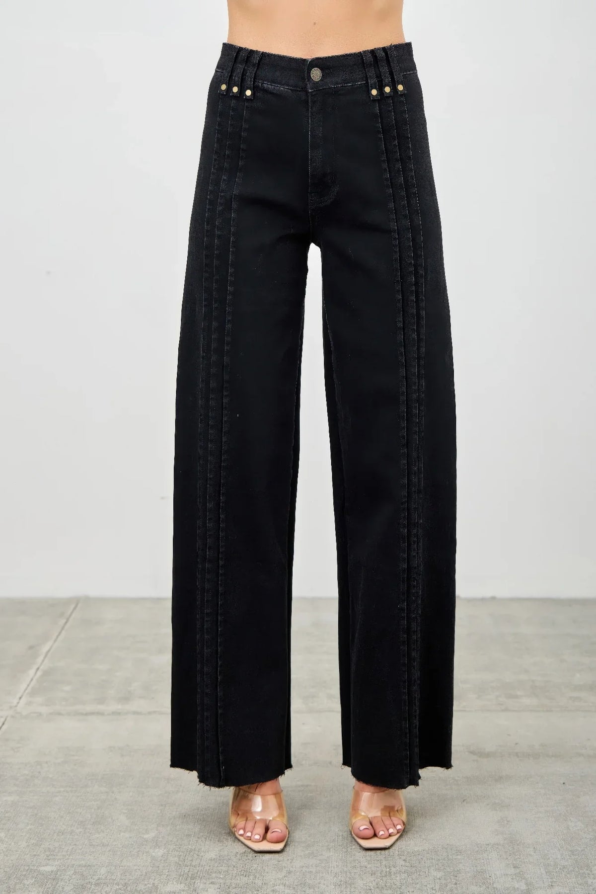 High-waisted wide-leg black jeans with front pintuck seams and gold button accents.
