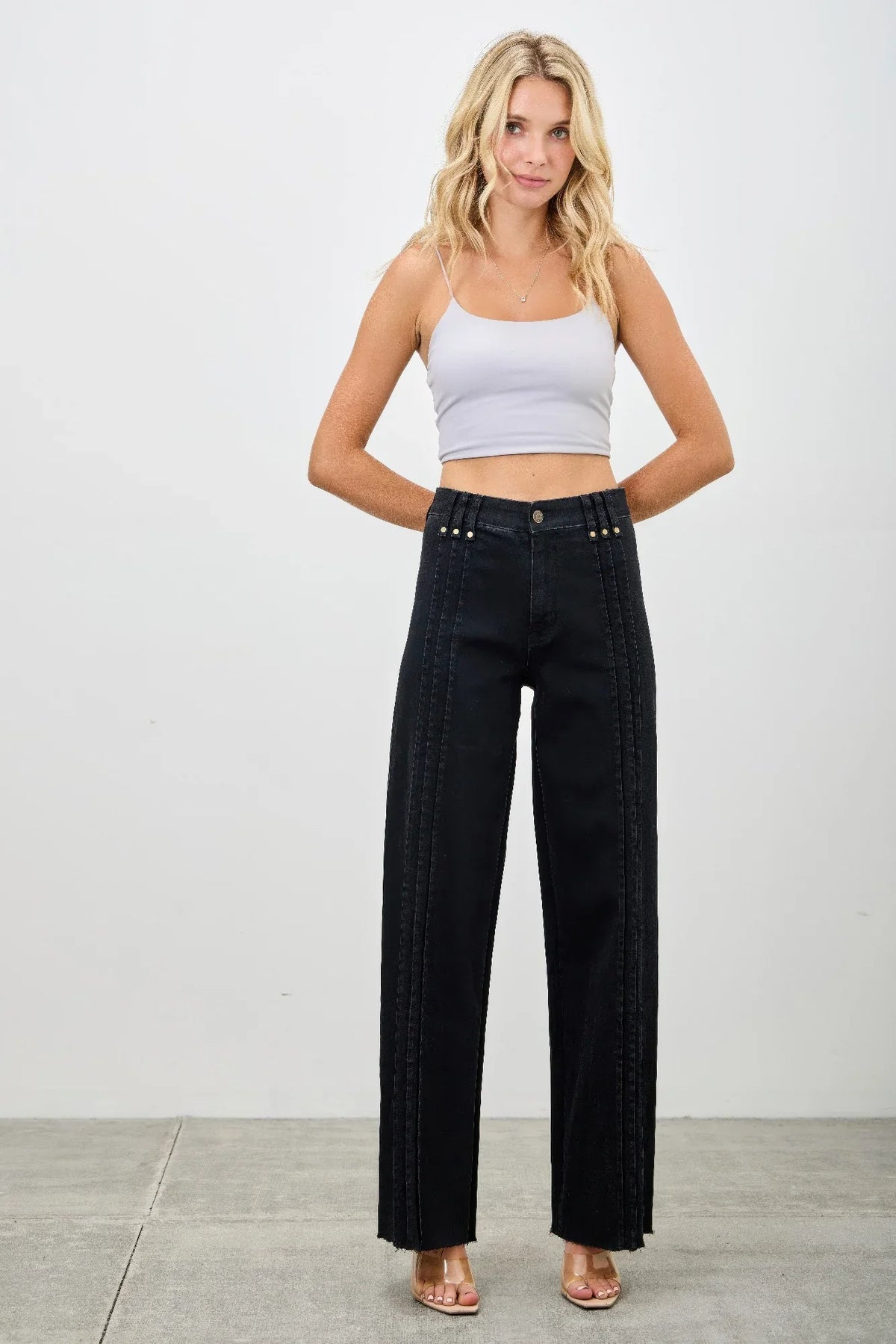 Woman wearing black high-waisted wide-leg jeans with front seam detailing and a light crop top