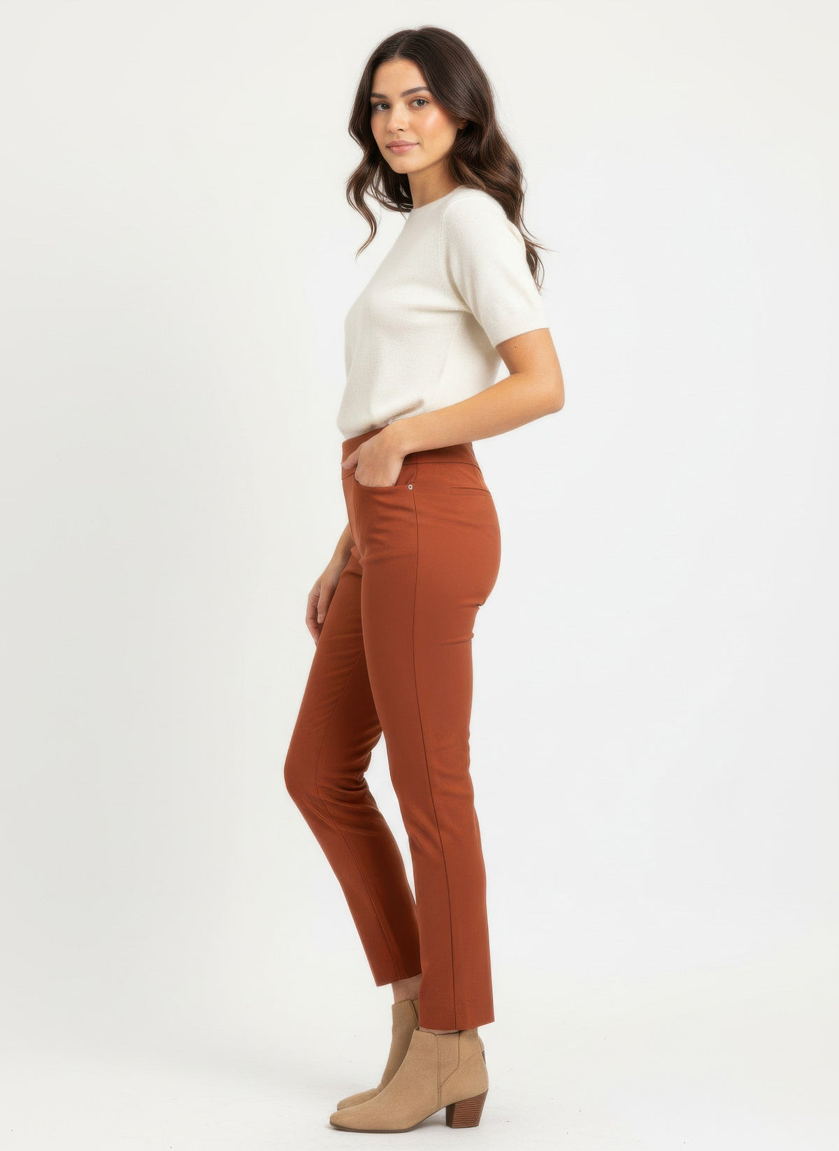 Woman wearing a white short sleeved top and cropped pull on pants and beige ankle boots on a white background