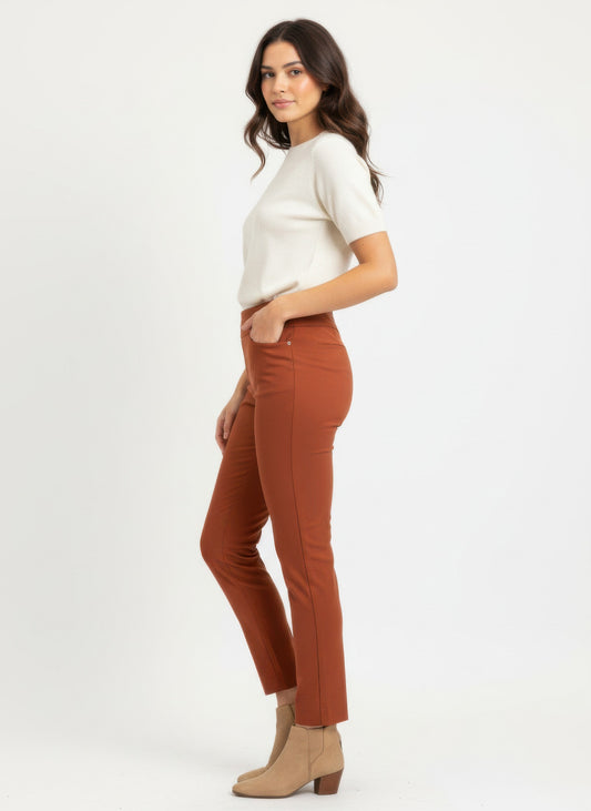 Woman wearing a white short sleeved top and cropped pull on pants and beige ankle boots on a white background