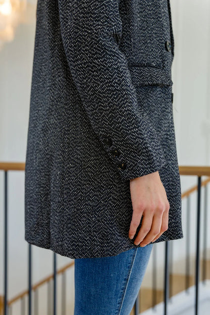 Black button-down blazer jacket with a textured dot pattern, worn with blue jeans