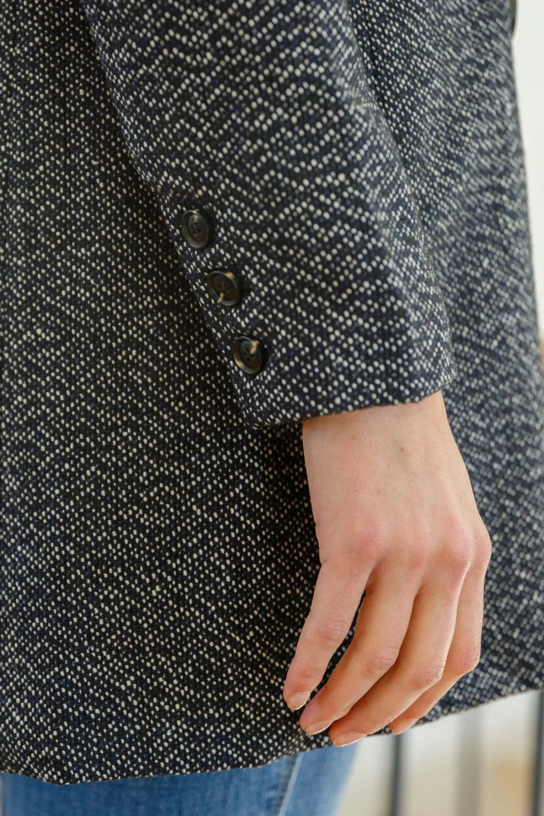 Close-up of textured black and white button-down blazer sleeve with button details