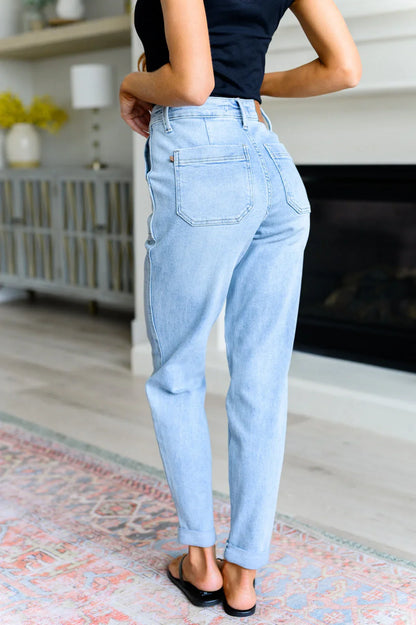 Woman in light wash high-rise jeans and black top standing in modern living room