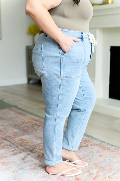 Woman wearing light wash relaxed fit jeans with front pockets and drawstring waist