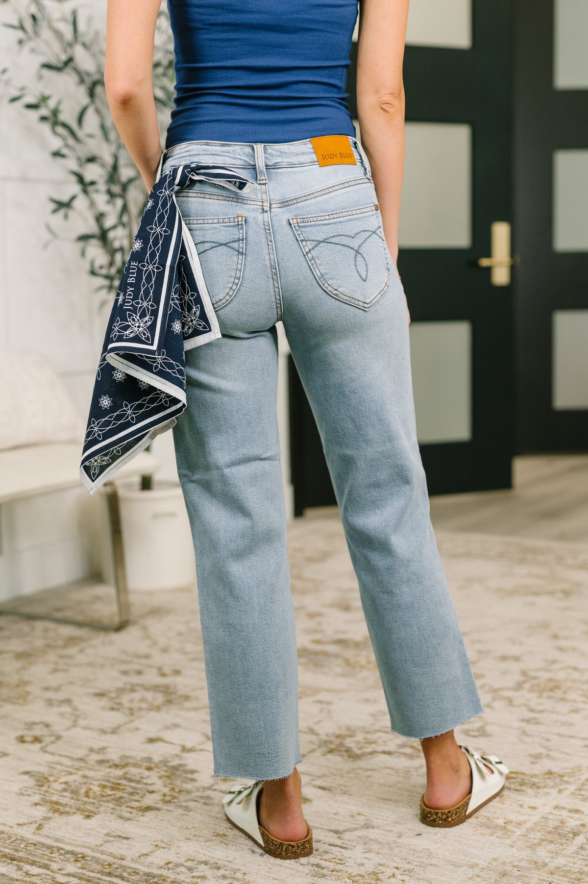 Person wearing blue jeans and a blue top, holding a patterned cloth.