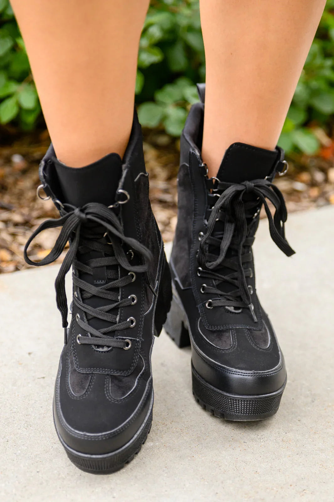Women’s black lace-up combat boots with chunky tread sole, shown outdoors on feet