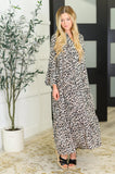 Woman wearing a relaxed fit leopard print maxi dress with long sleeves and black sandals indoors.