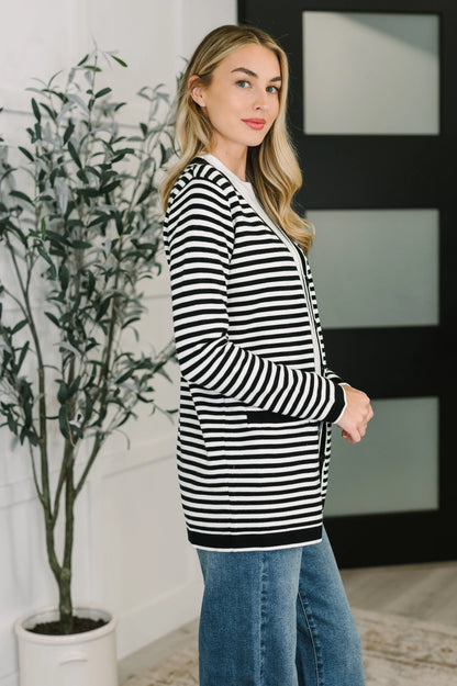 Woman wearing a black and white striped cardigan with blue jeans indoors