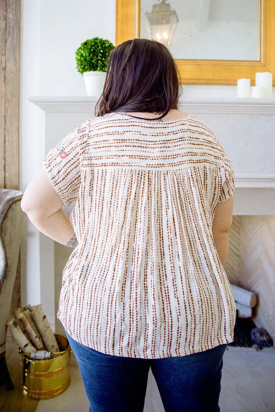 Back view of woman wearing a short-sleeve striped blouse with relaxed fit and blue jeans