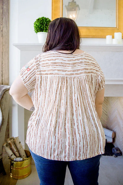Back view of woman wearing a short-sleeve striped blouse with relaxed fit and blue jeans