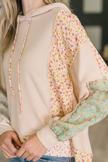 Beige hooded pullover with floral patchwork panels and relaxed fit, worn by woman