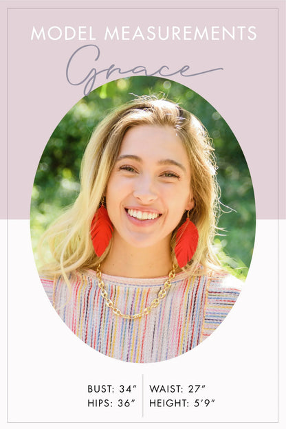 Smiling woman with blonde hair, red feather earrings, gold chain necklace, and striped top; model measurements listed.