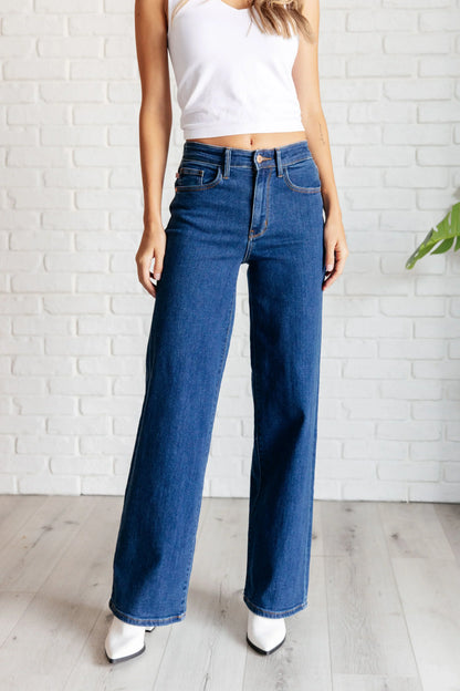 Woman wearing high-rise vintage wide-leg jeans and white crop top, standing indoors