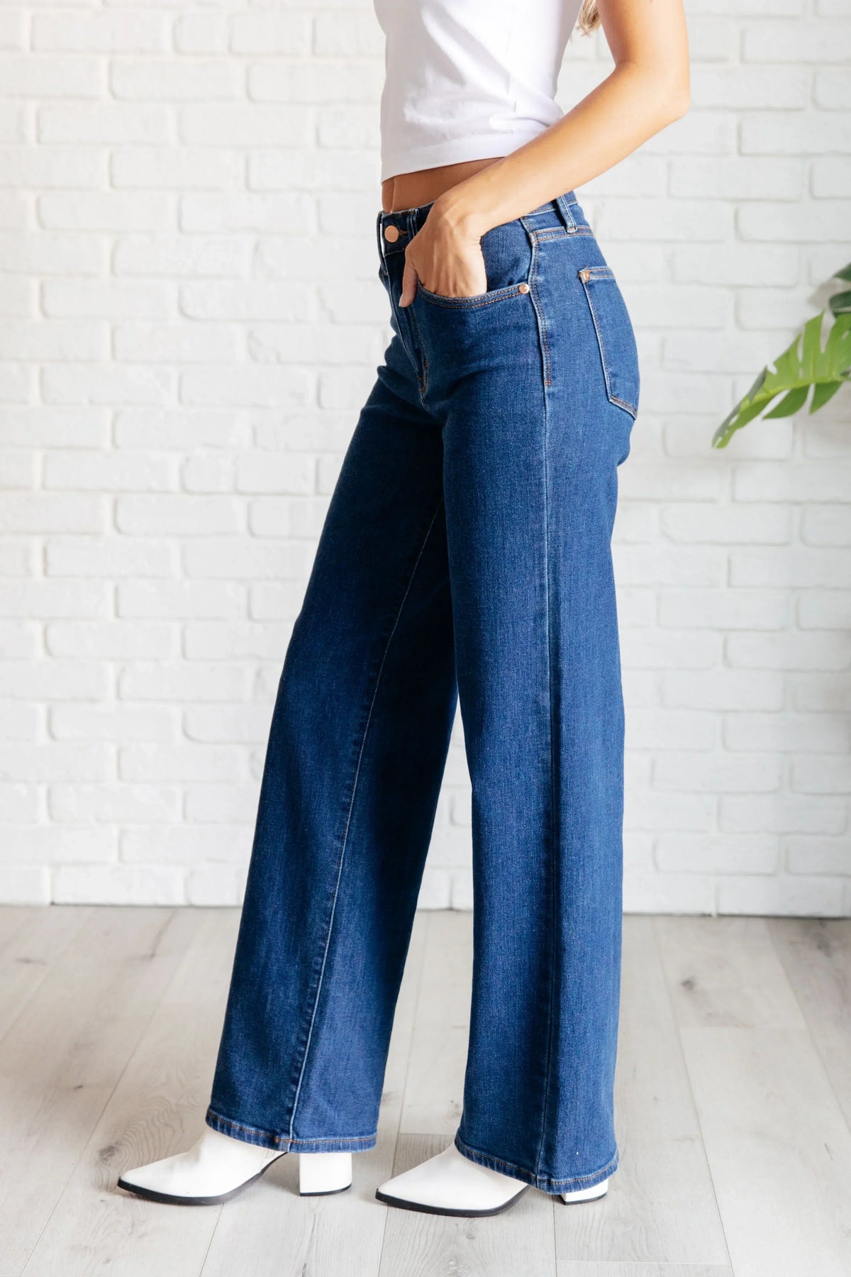 Woman wearing high-rise vintage wide leg jeans with white heeled boots, side view