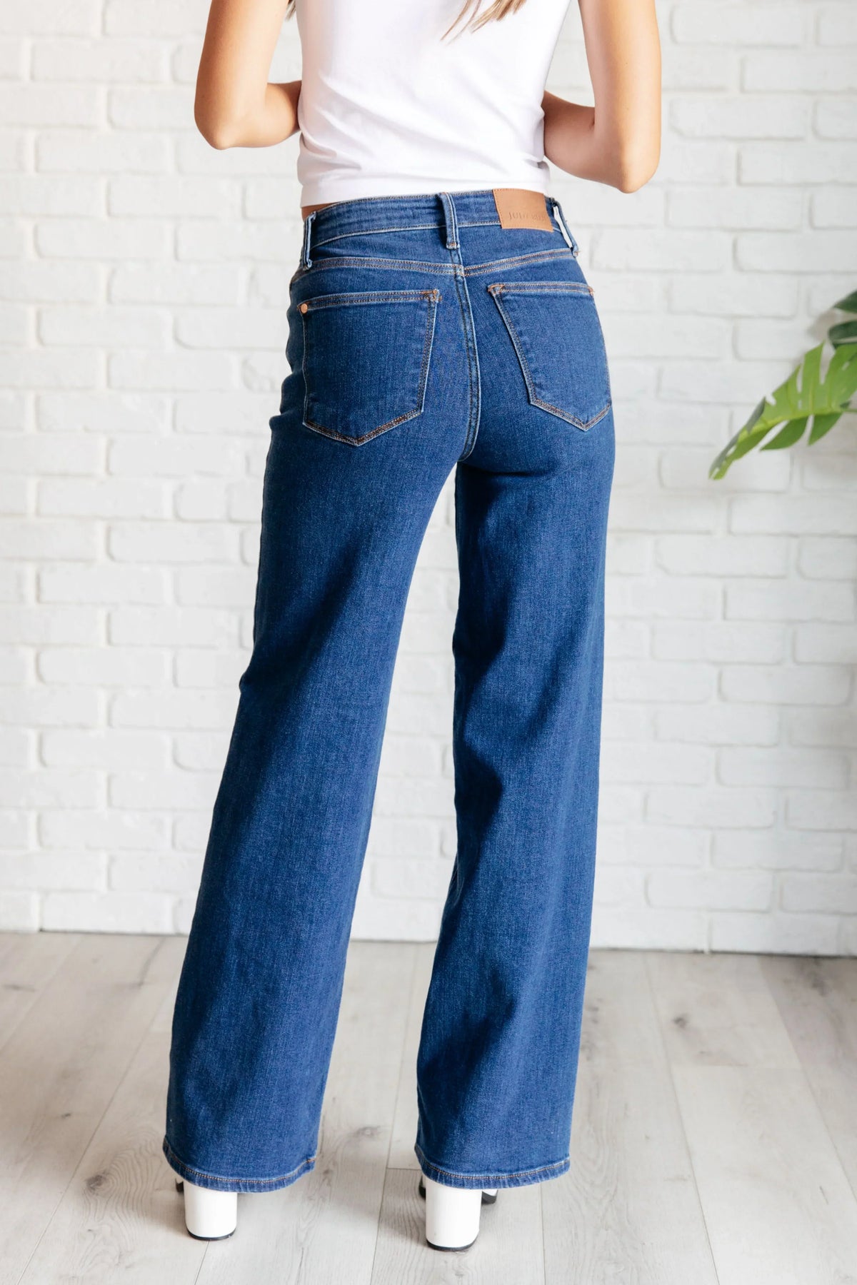 Woman wearing high rise vintage wide leg jeans in blue denim, back view.