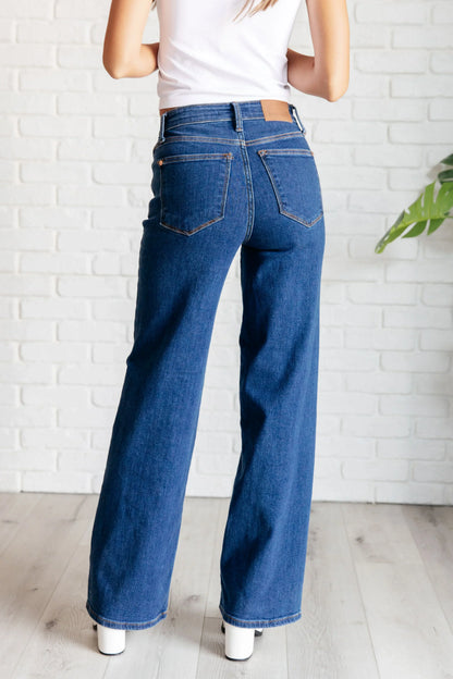 Woman wearing high rise vintage wide leg jeans in blue denim, back view.
