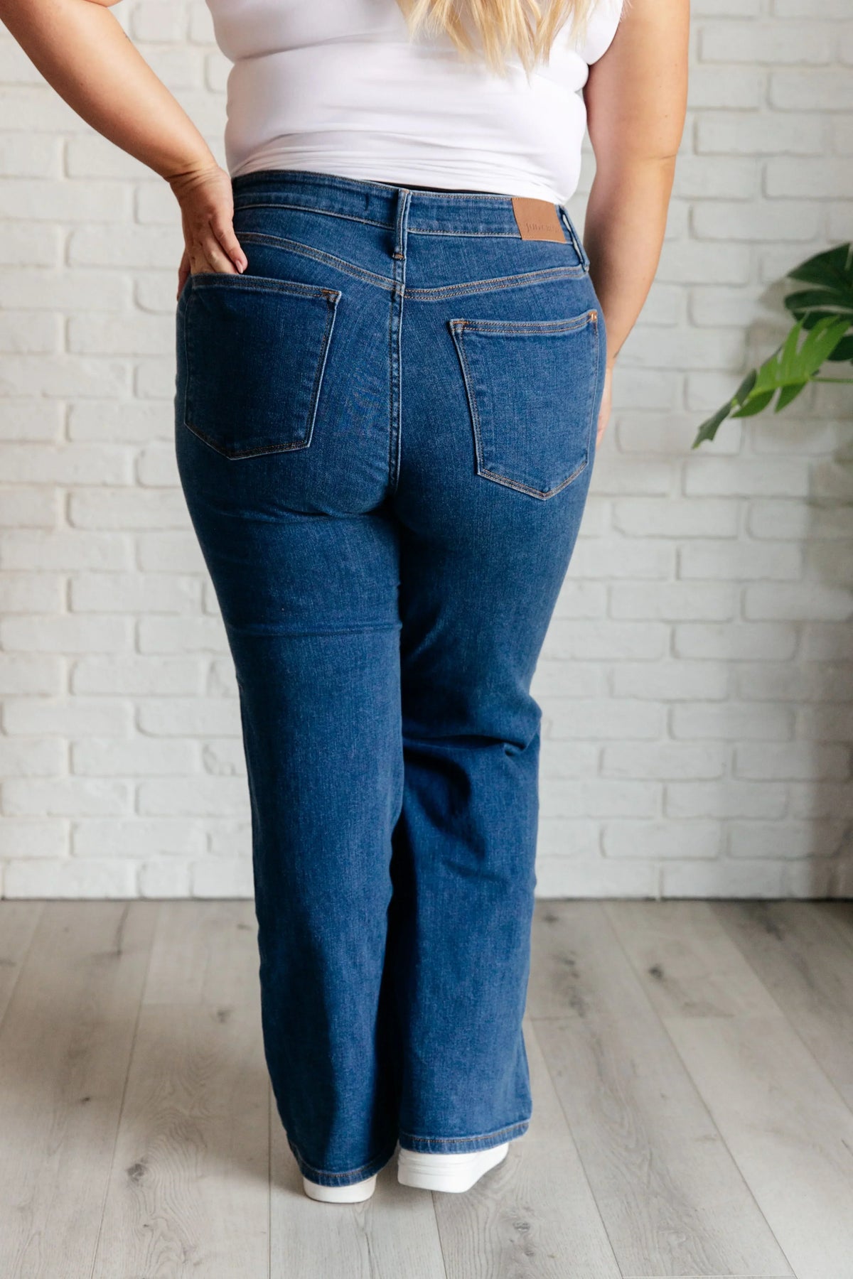 Back view of high rise vintage wide leg jeans in dark blue denim on a model indoors