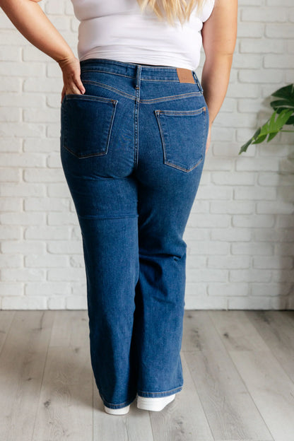 Back view of high rise vintage wide leg jeans in dark blue denim on a model indoors