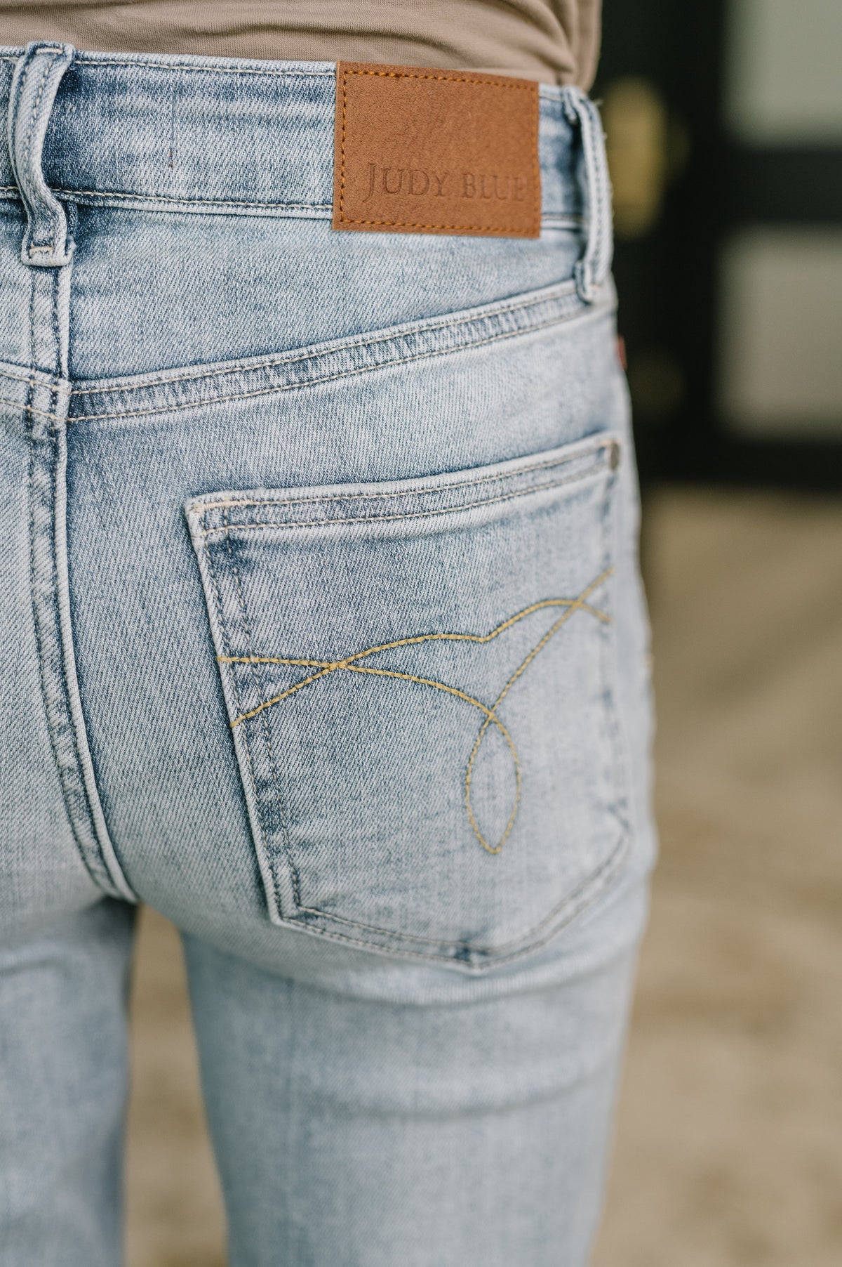 Close-up of light blue jeans with a brand label on the back pocket.