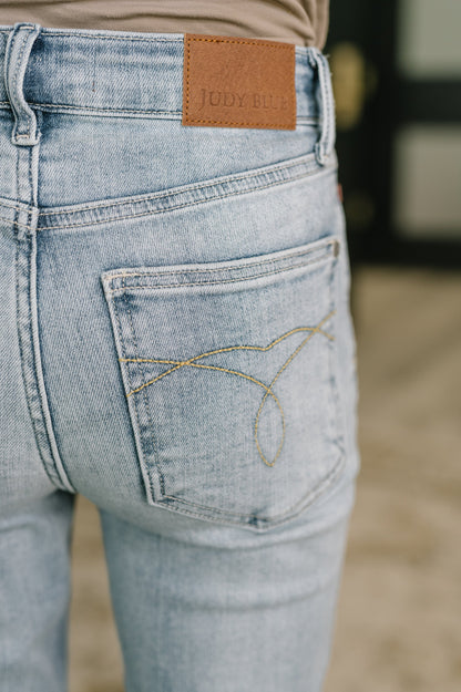 Close-up of light blue jeans with a brand label on the back pocket.