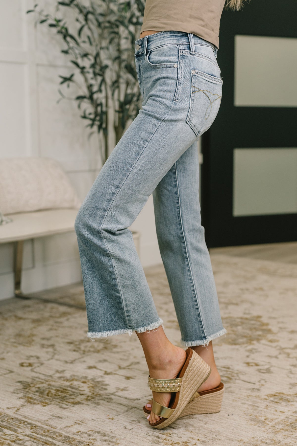 Person wearing light blue jeans and brown sandals on a patterned rug.