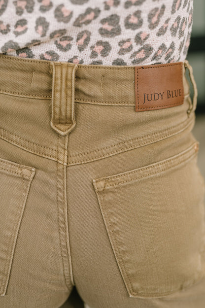 Close-up of beige pants with a brown label reading 'Judy Blue'.