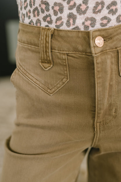 Close-up of brown pants with a patterned top in the background