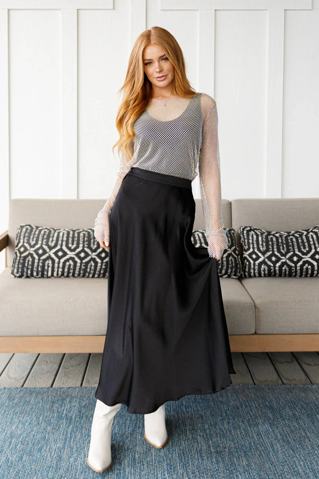 Woman wearing a black skirt and white top in a living room setting