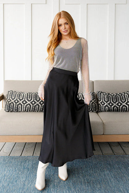 Woman wearing a black skirt and white top in a living room setting