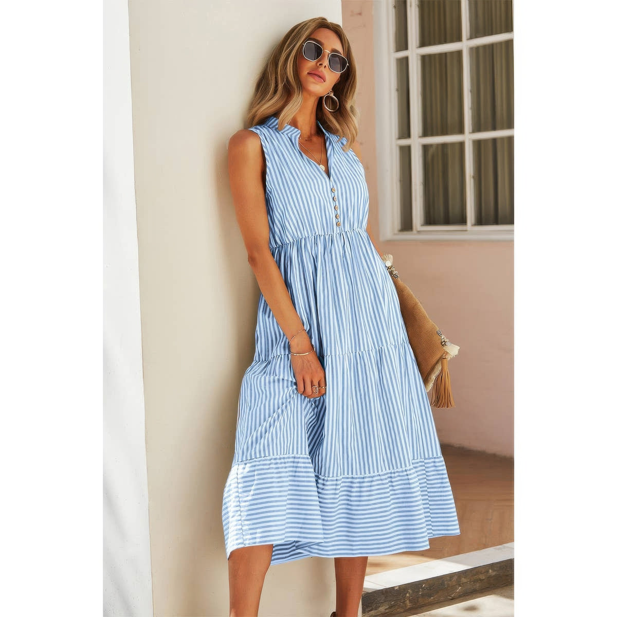 A woman wearing a striped sleeveless v-neck a-line color block dress with a tiered skirt, standing outdoors next to a white column.