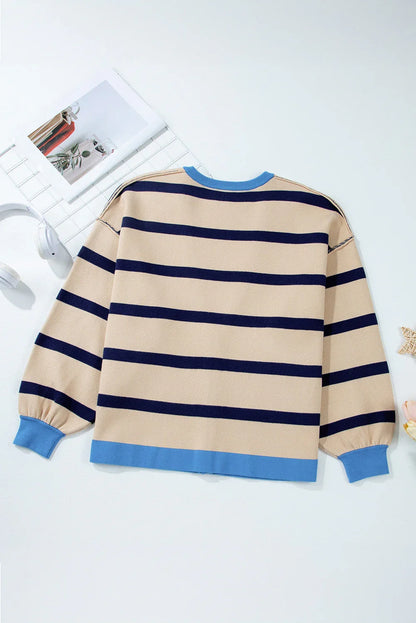 Beige and navy striped sweater with light blue cuffs and hem, laid flat on white background.