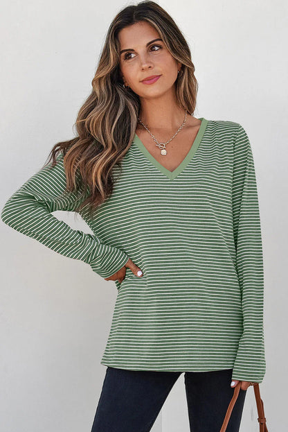 Woman wearing green and white striped long sleeve V-neck top with casual black pants