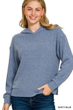 Woman wearing a dusty blue ribbed knit hoodie with relaxed fit and long sleeves.