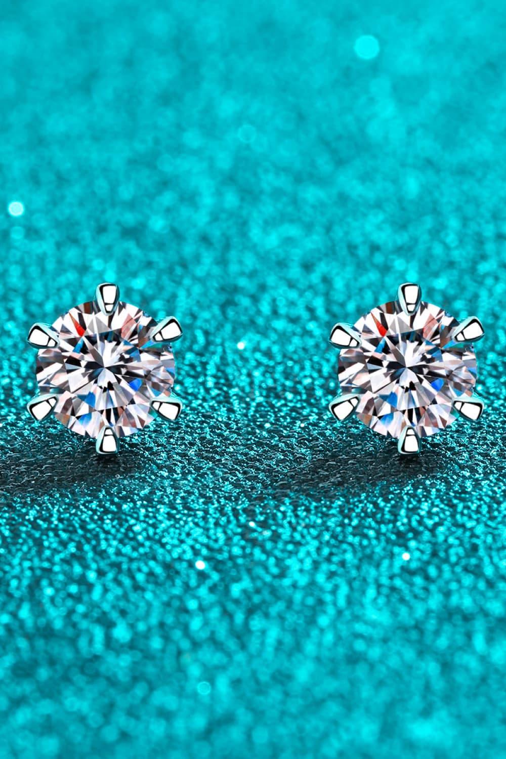 Round diamond stud earrings with prong settings on sparkling teal background