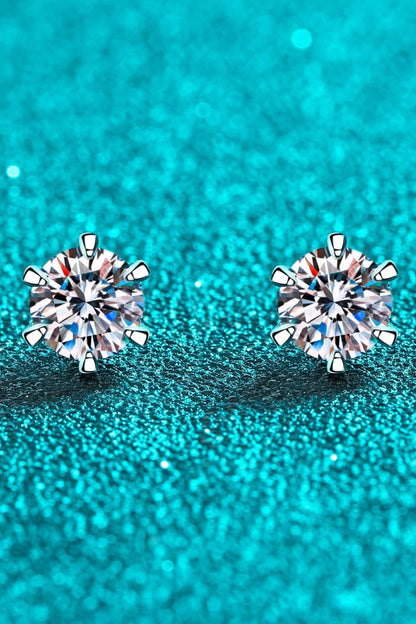 Round diamond stud earrings with prong settings on sparkling teal background