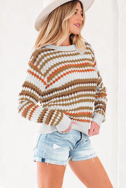 Woman in a patterned knit sweater with earth tones, denim shorts, and a wide-brim hat