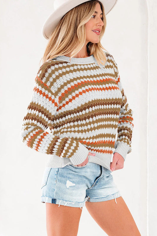 Woman in a patterned knit sweater with earth tones, denim shorts, and a wide-brim hat