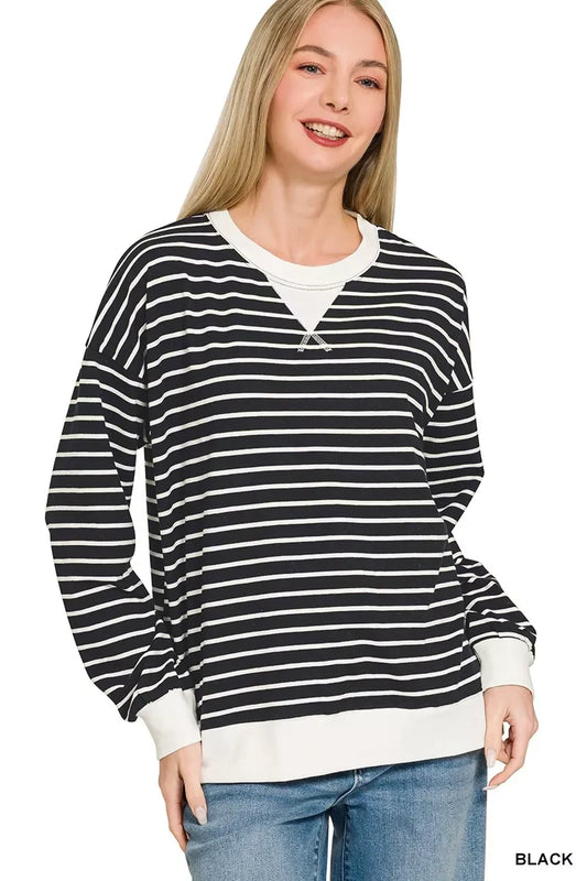 Woman wearing a black and white striped long sleeve sweater with relaxed fit and white cuffs