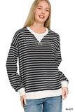 Woman wearing a black and white striped long sleeve sweater with relaxed fit and white cuffs