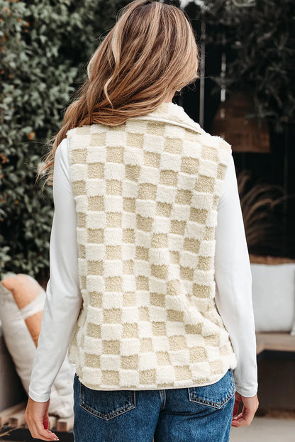 Woman wearing a cream and beige checkered sherpa vest and blue jeans outdoors