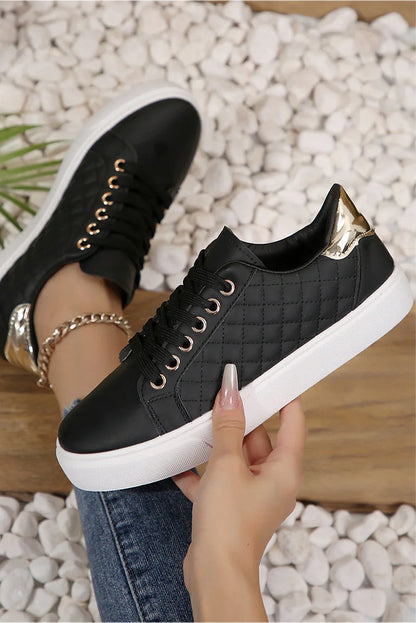 Black quilted sneakers with gold heel detail and white soles, styled with jeans