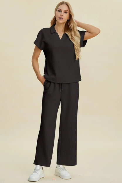 Woman in relaxed fit black short sleeve top and wide leg pants set, casual neutral background