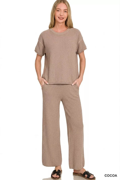 a woman wearing a taupe viscose round neck top pants set with black slides on a white background