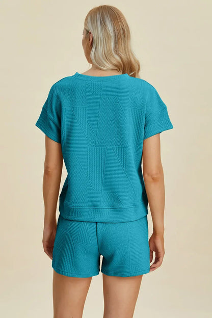 Woman wearing a textured turquoise short-sleeve top and matching shorts set, back view