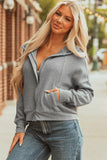 Woman in a casual gray zip-up hoodie and blue jeans standing outdoors