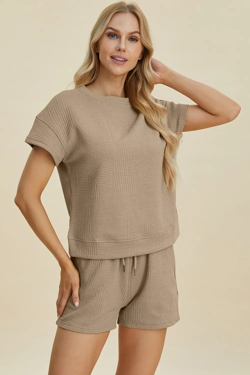Woman wearing a textured beige short-sleeve top and matching drawstring shorts set