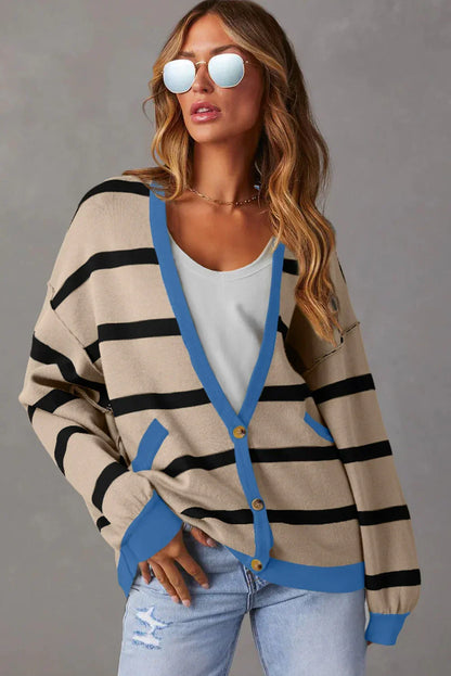 Woman in beige and black striped cardigan with blue trim, sunglasses, and light wash jeans.
