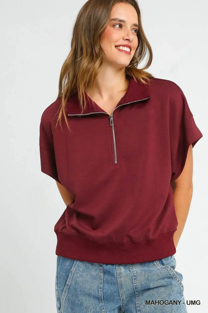 Woman wearing a relaxed fit mahogany short sleeve zip collar top with blue denim jeans.